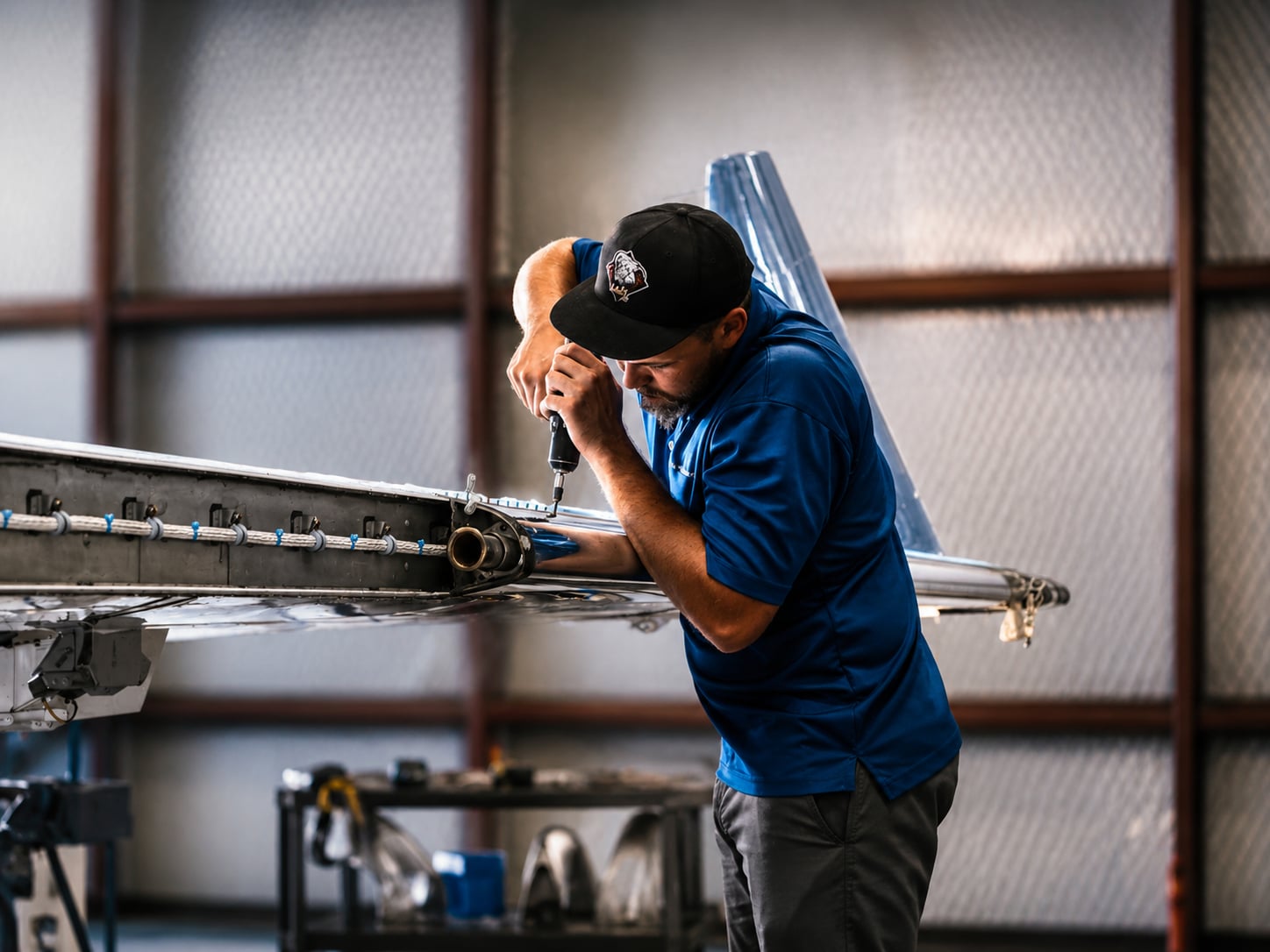 Plane Place Aviation technician drilling into a wing component during structural work